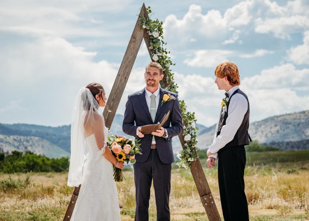 Bride and groom sharing first kiss at outdoor wedding ceremony Colorado